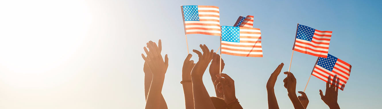 people with their hands in the air holding American flags