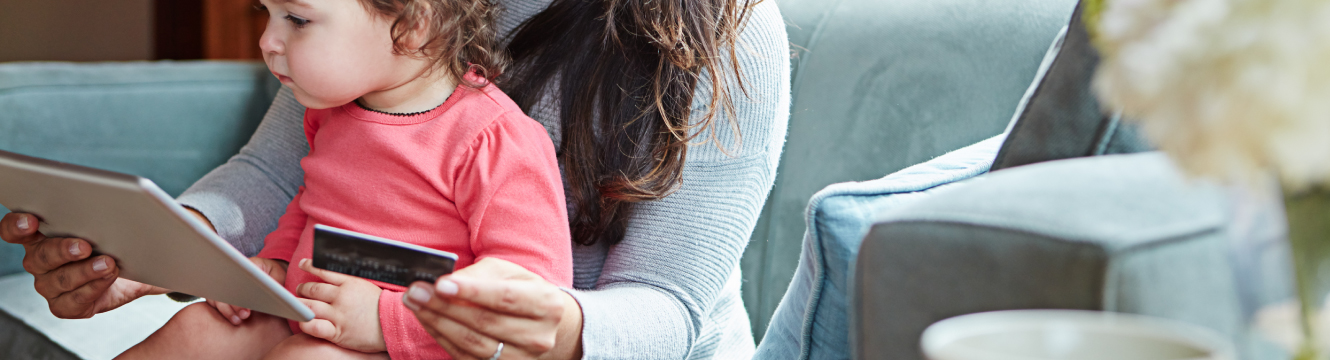 A woman with a little girl on lap using her iPad and debit card